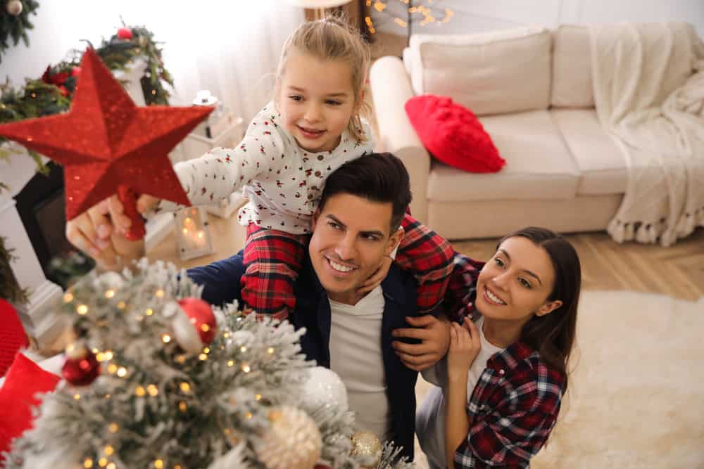 family placing a star on a Christmas tree