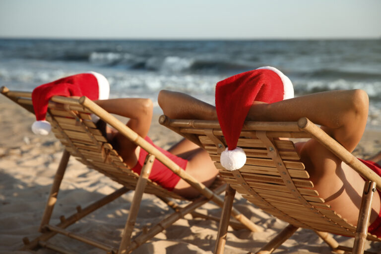 two people laying on beach chairs with Santa hats
