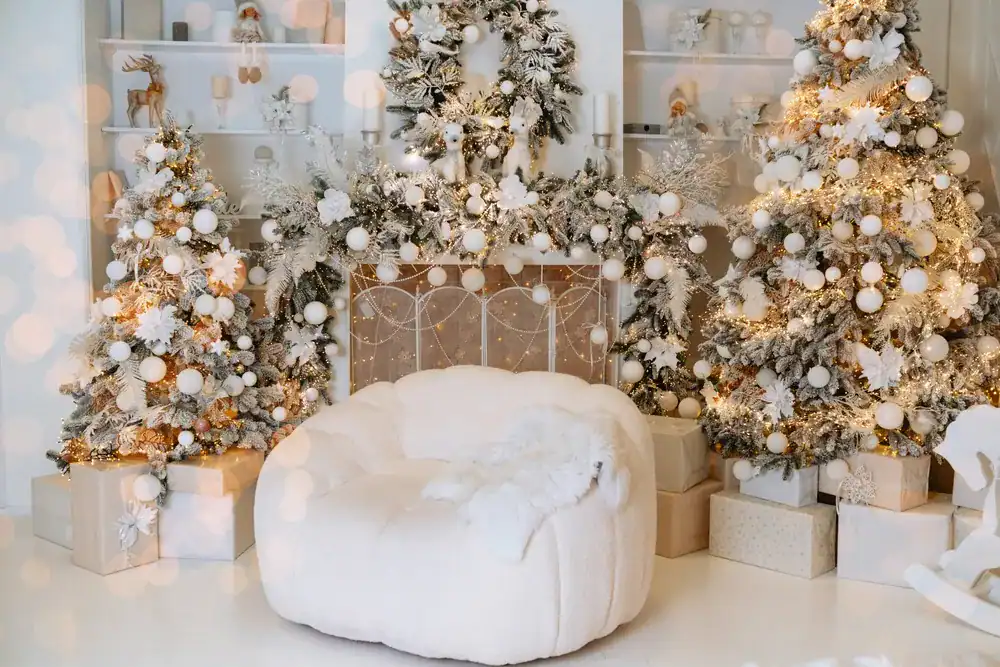 white christmas decorations inside a home with a white chair, fireplace, and Christmas trees