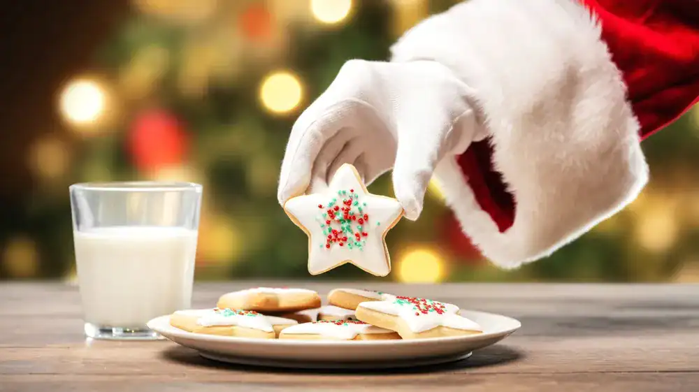 Santa Claus holding a Christmas sugar cookie.